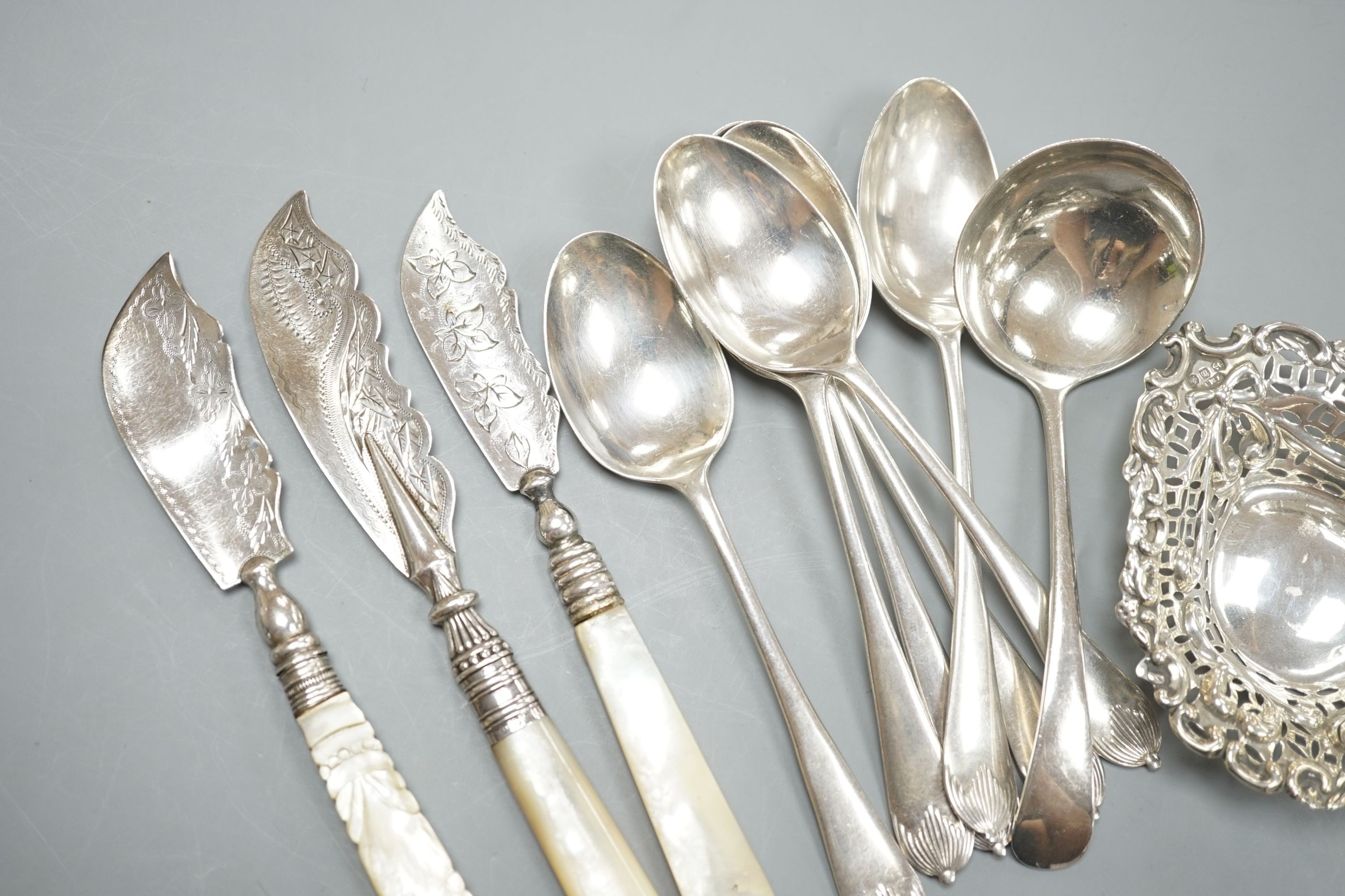 A late Victorian repousse silver bonbon dish, 91mm an assorted silver cutlery including three Victorian mother of pearl handled butter knives, a sauce ladle and two sets of six spoons including soup, weighable silver 11.